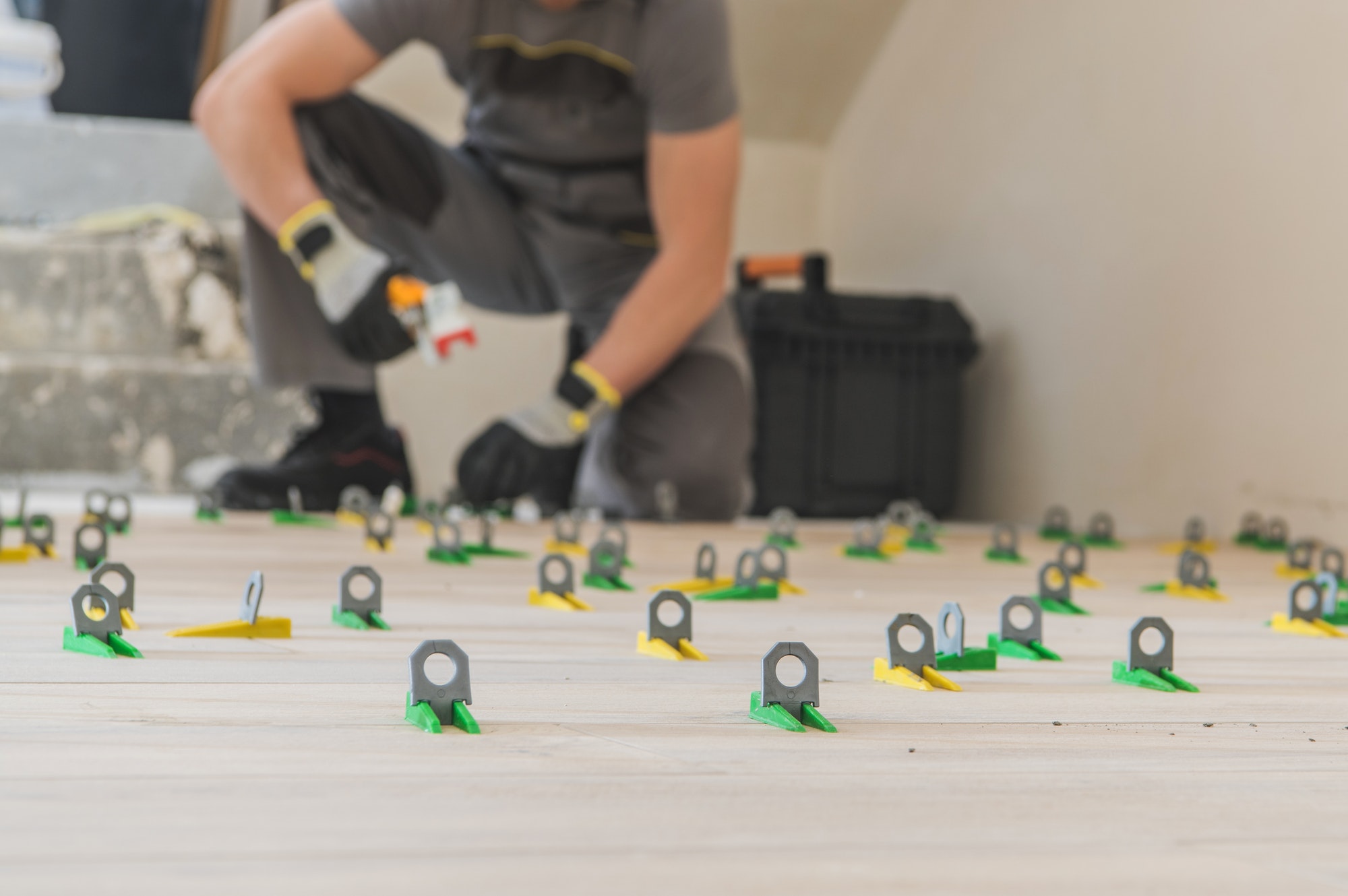 Contractor installing a floor tile leveling system during a flooring project.