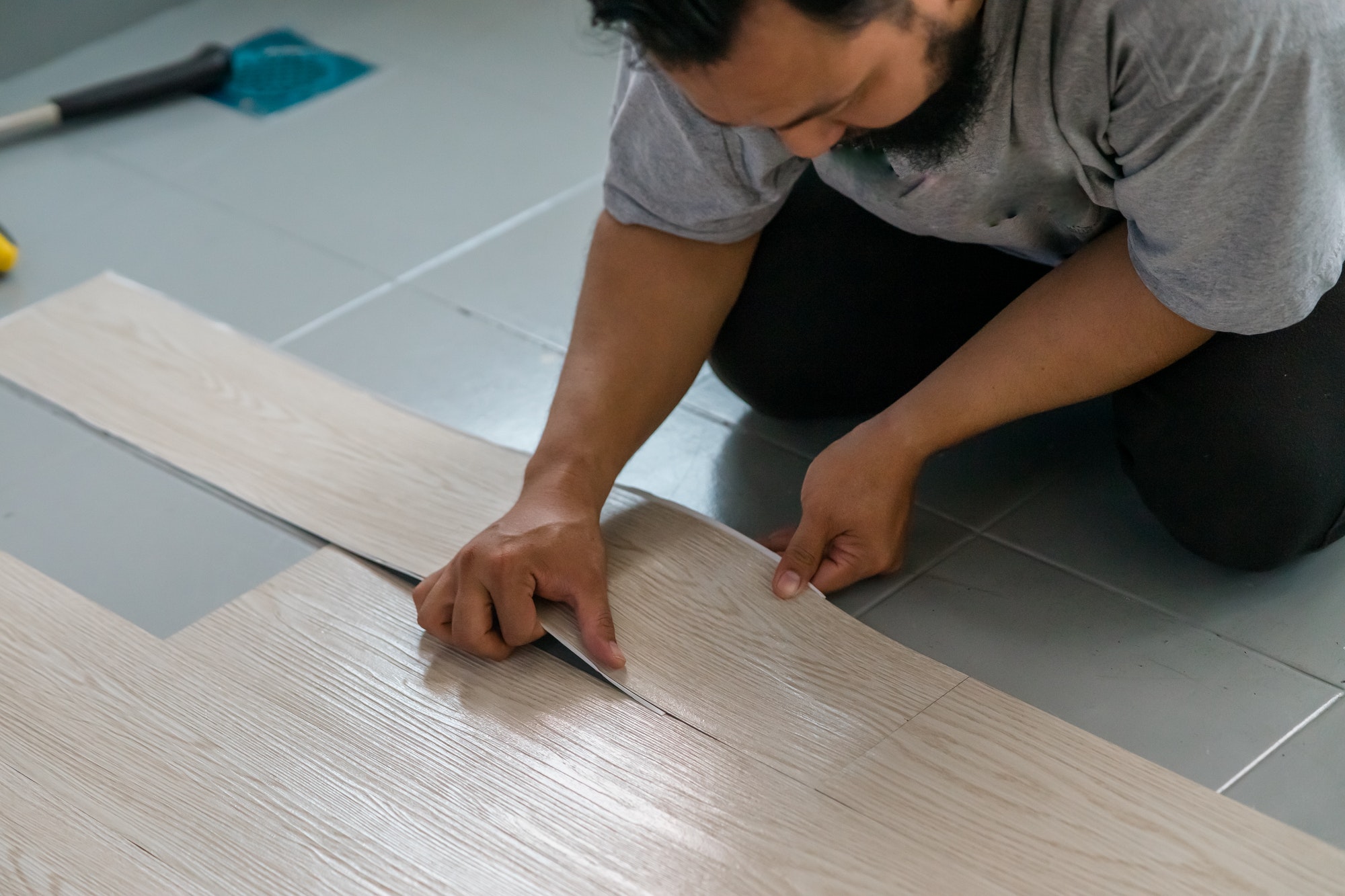 Worker installing luxury vinyl flooring panels in a home