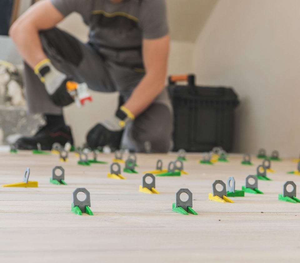Contractor installing a floor tile leveling system during a flooring project.